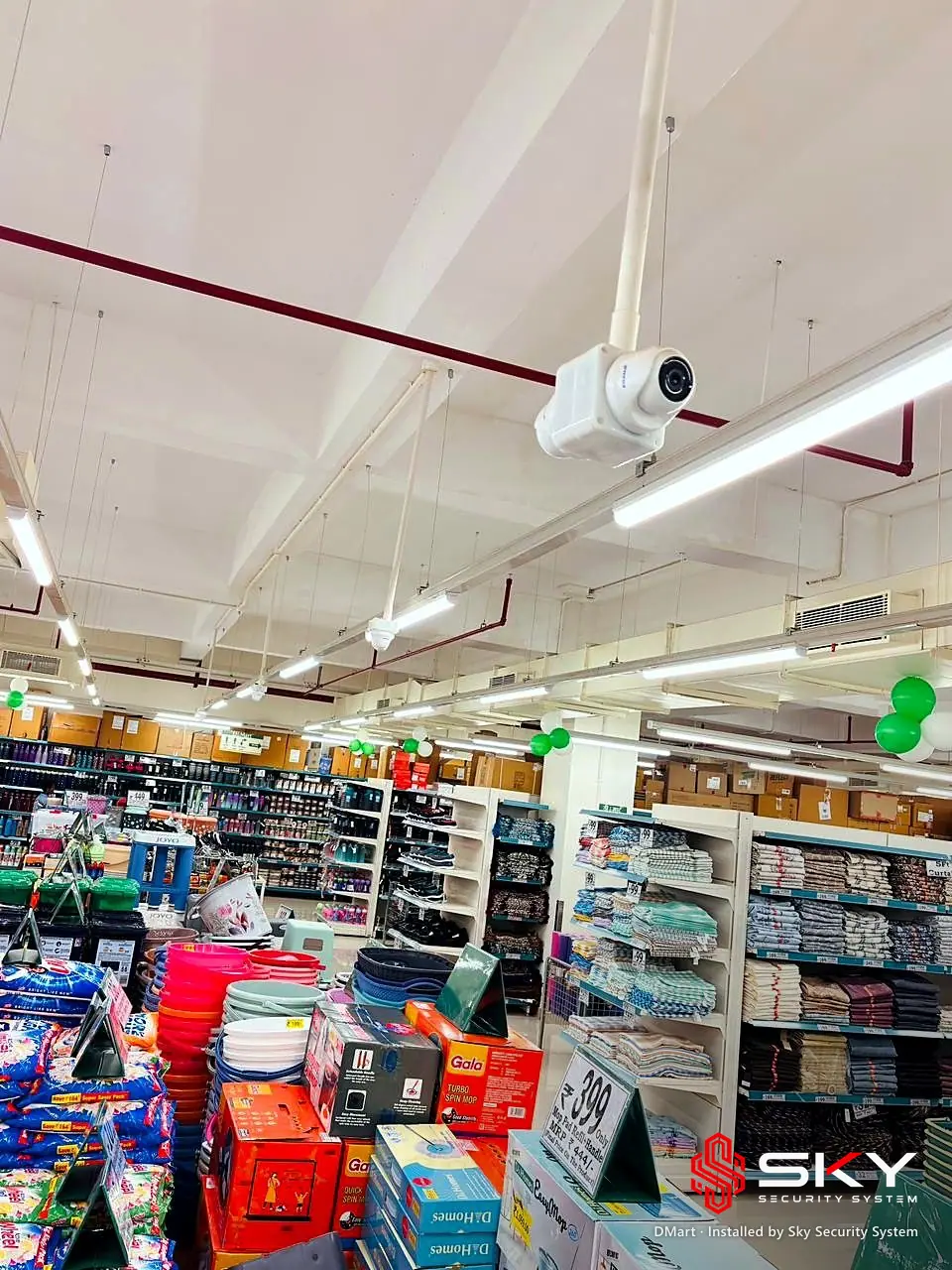 Ceiling camera above a store aisle at the DMart site. Security and ELV work by Sky Security System.